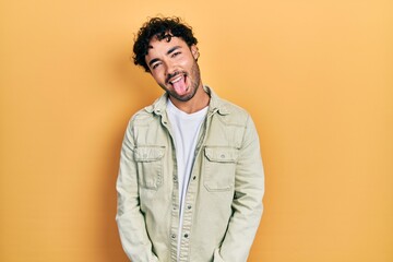 Poster - Young hispanic man wearing casual clothes sticking tongue out happy with funny expression. emotion concept.