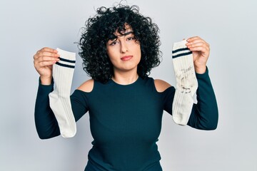 Poster - Young middle east woman holding socks relaxed with serious expression on face. simple and natural looking at the camera.