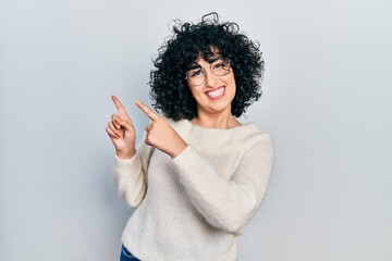 Wall Mural - Young middle east woman wearing casual white tshirt smiling and looking at the camera pointing with two hands and fingers to the side.