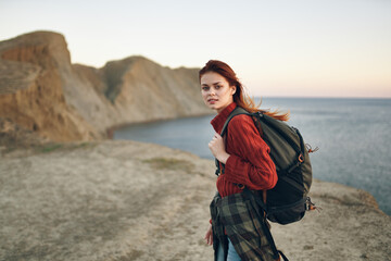 beautiful woman with a backpack in the mountains red sweater model hairstyle ocean sea