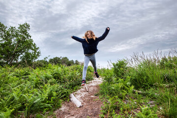 cute young girl running and jumping in a beautiful forest