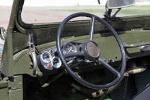 Old Steering Wheel And Analog Appliances Dashboard In Interior Of Old Khaki Retro Soviet Military 4x4 Car Closeup At Sunny Day