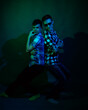 © ISliM - Two young men in plaid shirts dance in the studio with multicolored light