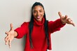 © Krakenimages.com - African american woman wearing casual winter sweater looking at the camera smiling with open arms for hug. cheerful expression embracing happiness.