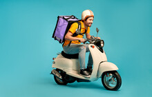 Young Courier, Delivery Man In Uniform With Thermo Backpack On A Moped Isolated On Blue Background. Fast Transport Express Home Delivery. Online Order.