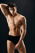 © SHOTPRIME STUDIO - man with pumped up abs hold hands above his head in a dark background