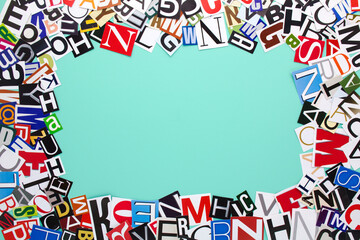 Alphabet letters cutting from paper magazine on azure green background with copy space for text. Colorful abstract collage from clippings with newspaper magazine letters.