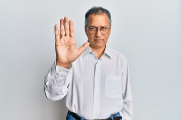 Sticker - Middle age indian man wearing casual clothes and glasses doing stop sing with palm of the hand. warning expression with negative and serious gesture on the face.