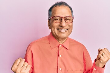 Sticker - Middle age indian man wearing casual clothes and glasses very happy and excited doing winner gesture with arms raised, smiling and screaming for success. celebration concept.