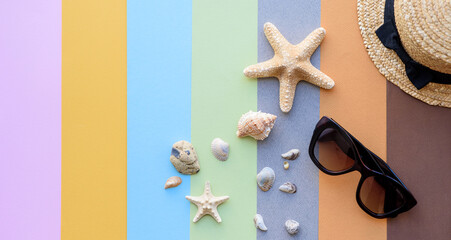 Beach accessories: glasses and hat with shells and sea stars on a colored background