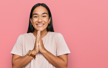 Canvas Print - Young asian woman wearing casual clothes praying with hands together asking for forgiveness smiling confident.