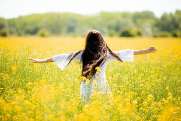 Wall Mural - Young woman in the rapeseed field