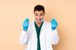 © luismolinero - Young dentist man holding tools isolated on beige background making money gesture