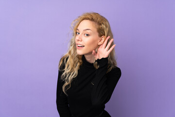 Poster - Young blonde woman isolated on purple background listening to something by putting hand on the ear