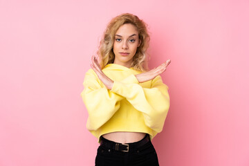 Poster - Young blonde woman wearing a sweatshirt isolated on pink background making NO gesture