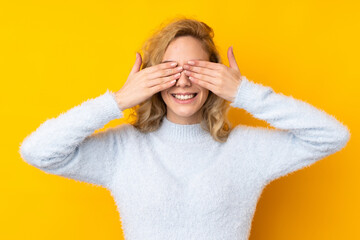 Poster - Young blonde woman isolated on yellow background covering eyes by hands