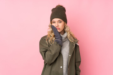 Poster - Young girl with winter hat isolated on pink background unhappy and frustrated