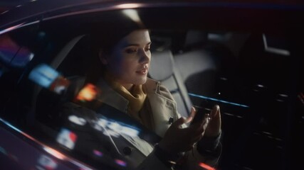 Wall Mural - Stylish Female is Commuting Home in a Backseat of a Taxi at Night. Beautiful Woman Passenger Using Smartphone and Looking Out of Window while in a Car in Urban City Street with Working Neon Signs.