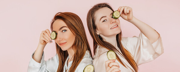 Wall Mural - two girls make homemade face beauty masks. cucumbers for the freshness of the skin around the eyes. 