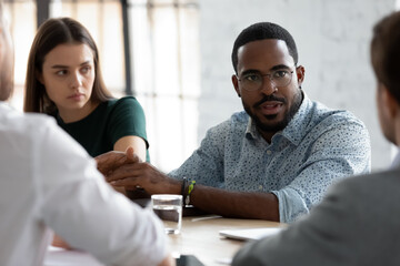 Wall Mural - Focused African American coach teaching group of interns, mentoring new employees, training company staff, speaking and explaining tasks. Business leader meeting and negotiating with partners