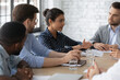 © fizkes - Focused Indian female employee presenting and explaining project plan and strategy to team and boss, reporting for work. Manager sharing ideas with group on corporate meeting with executive