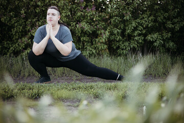 Wall Mural - Young overweight woman doing yoga at summer meadow