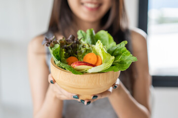 Eat high fiber and low calories foods for good health.Young woman eating bowl of fresh salad and pure water in the morning.