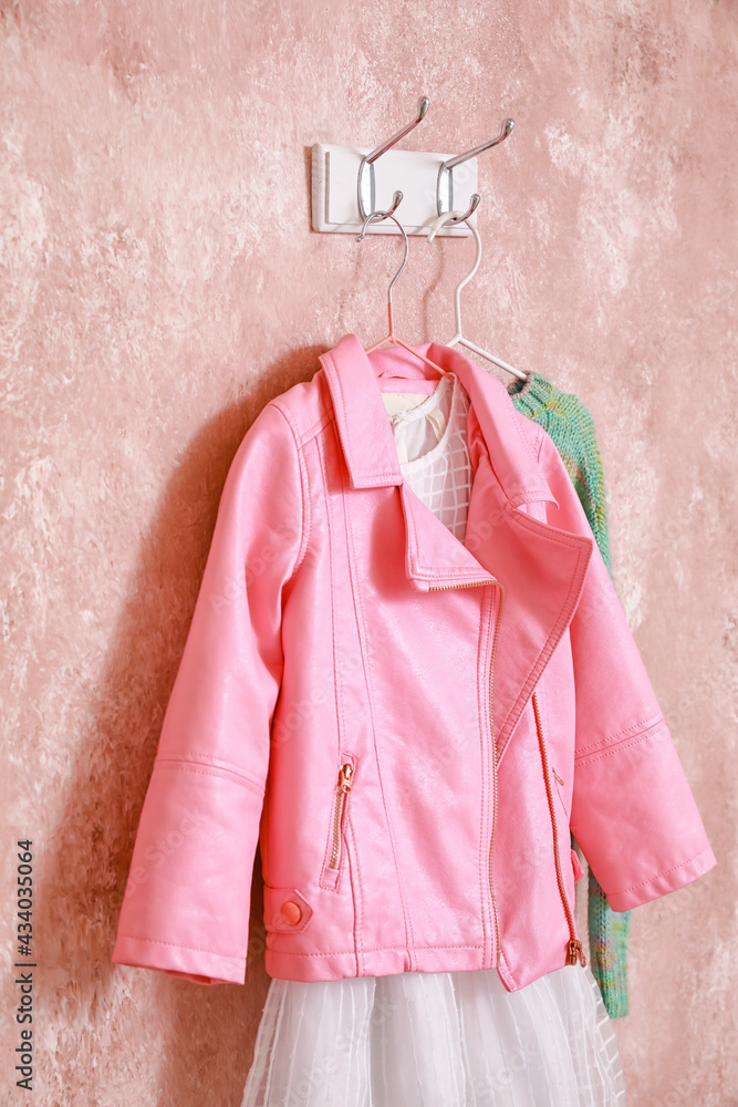 Hanger with stylish clothes on color background