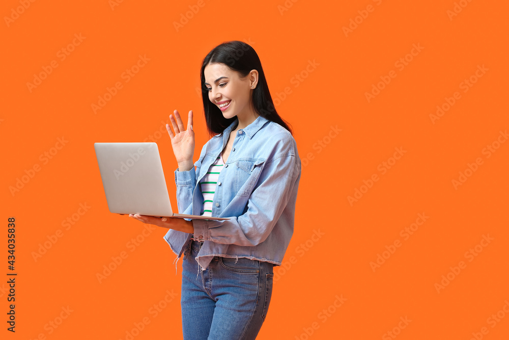 Young woman with laptop on color background