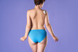 Woman with bare back applying body foam on her shoulder on purple background