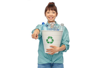 Sticker - recycling, waste sorting and sustainability concept - smiling young asian woman holding rubbish bin with plastic bottles pointing finger to camera over white background