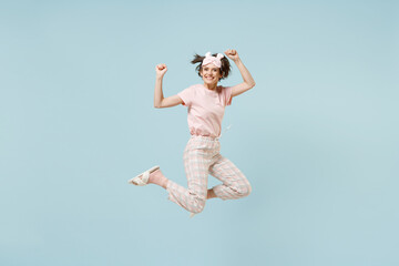 Wall Mural - Full length young overjoyed woman in pajamas jam sleep eye mask rest relaxing at home jump high do winner gesture clench fist isolated on pastel blue background studio Good mood night bedtime concept