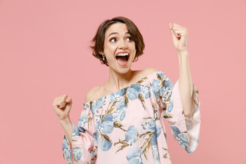 Wall Mural - Young overjoyed happy stylish caucasian woman with short hairdo in trendy blouse do winner gesture clench fist celebrating isolated on pastel pink background studio portrait. People lifestyle concept.