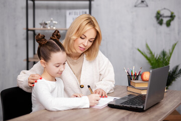 Wall Mural - school, homework and distance education concept - school girl doing homework with her mother at home