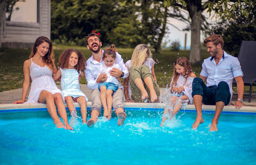 Large group of people sitting by the swimming pool.