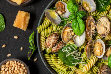 Wall Mural - Salad made of pasta fusilli, seafood vongole, spinach, parmesan cheese and pine nut in a plate on black table. Top view