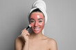 © New Africa - Woman applying pomegranate face mask on grey background