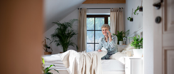 Wall Mural - Happy senior woman using smartphone in bed at home.