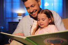 Father Reading Bedtime Story To His Daughter At Home