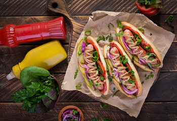 Wall Mural - Hot dog with  pickles, tomato and lettuce on wooden background. Hotdog, american cuisine. Top view, above, copy space