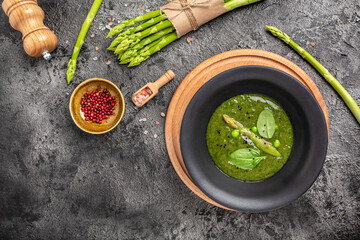 Canvas Print - Delicious soup with asparagus in ceramic bowl, on rustic wooden background. Clean eating, dieting, vegan, vegetarian, healthy food concept. top view