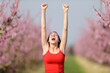 Excited woman raisng arms showing armpit in nature
