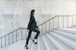 © Who is Danny - Career success concept with young woman climbs the stairs to the light in abstract building with stylish wall and light stairway.
