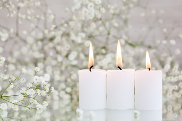 Burning candles and white flowers gypsophila on table with space for text.