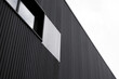 Black and white corrugated iron sheet used as a facade of a warehouse or factory with a windows. Texture of a seamless corrugated zinc sheet metal aluminum facade. Architecture. Metal texture.