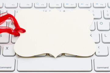 Wall Mural - Blank gift tag with red ribbon on gray keyboard