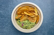 Top view of a portion of fried plantain chips with guacamole.