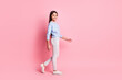 © deagreez - Full length body size profile side view of charming cheerful girl strolling step isolated over pink pastel color background