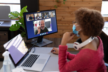 Wall Mural - African american businesswoman sitting at desk using computer having video call with colleagues