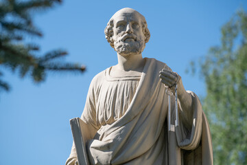 Antique statue of St. Peter with keys to the Kingdom of Heaven. Ancient statue on blue sky.